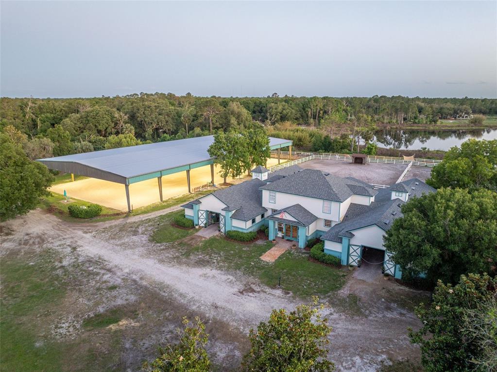 An aerial view shows a large house with a covered riding arena and a pond — 3287 N COUNTY ROAD 426, GENEVA, FL