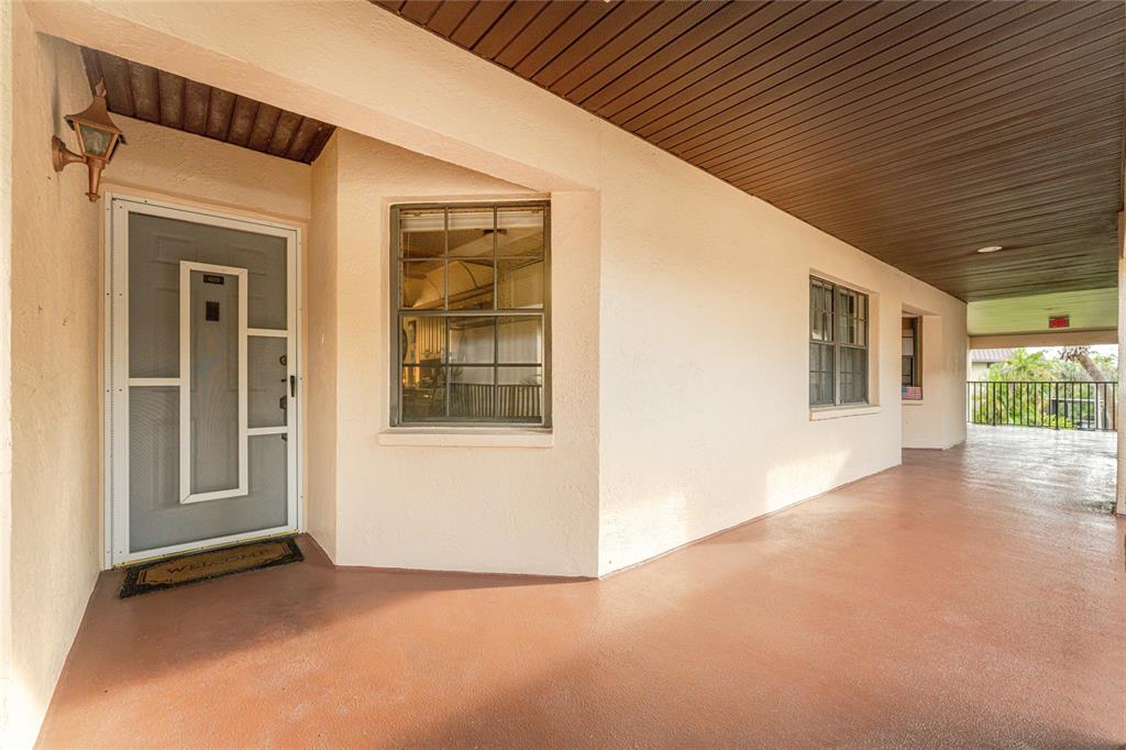 A covered outdoor walkway leads to a front door with a screen and windows — 23465 HARBORVIEW ROAD UNIT 1026, PUNTA GORDA, FL