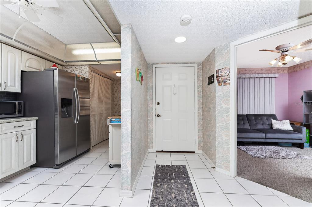 A tiled entryway leads to a kitchen on the left and a living room beyond — 23465 HARBORVIEW ROAD UNIT 1026, PUNTA GORDA, FL
