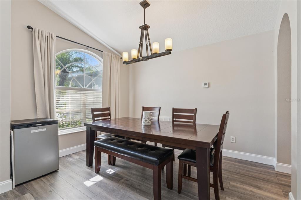 A dining room features a dark wood table, a bench, chairs, and a chandelier — 1024 DRIFT CREEK COVE, ORLANDO, FL