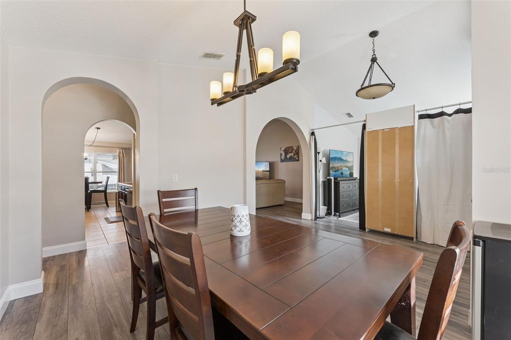 A dining room features a wooden table, dark chairs, and arched doorways leading to other rooms — 1024 DRIFT CREEK COVE, ORLANDO, FL