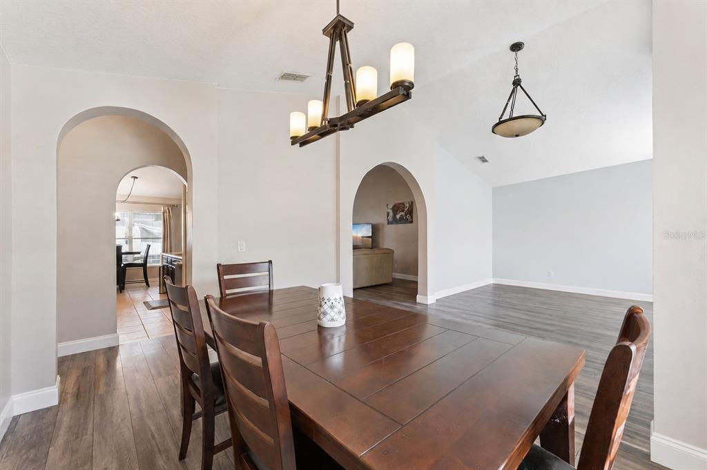 A dining room features a wooden table, arched doorways, and two hanging light fixtures — 1024 DRIFT CREEK COVE, ORLANDO, FL