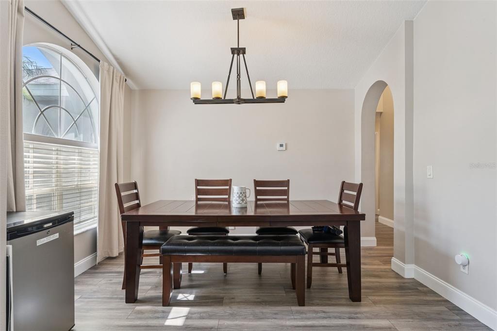 A dining room features a wooden table, four chairs, a bench, and a chandelier — 1024 DRIFT CREEK COVE, ORLANDO, FL