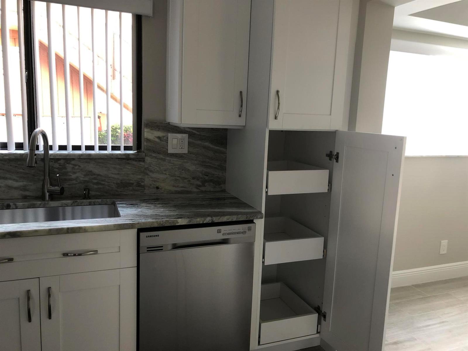 A kitchen features white cabinets, a stainless steel dishwasher, and a stone countertop — 15090 Ashland Place, Delray Beach FL 33484, DELRAY BEACH, FL