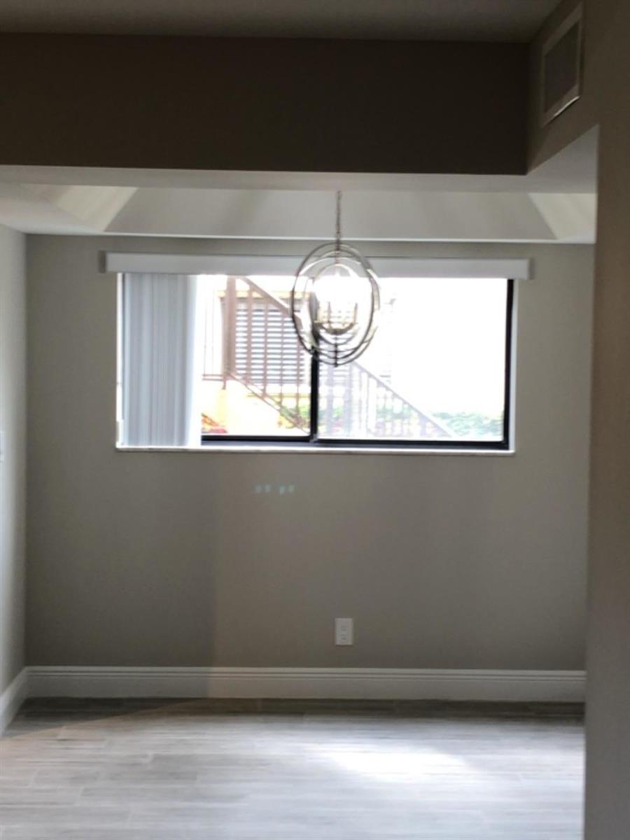 An empty dining area features a modern orb chandelier, a window, and light-colored flooring — 15090 Ashland Place, Delray Beach FL 33484, DELRAY BEACH, FL
