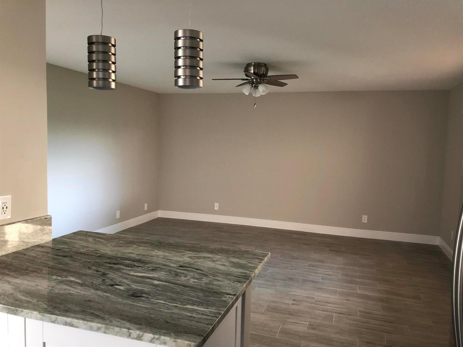 An empty room with gray walls, wood-look tile flooring, a ceiling fan, and pendant lights — 15090 Ashland Place, Delray Beach FL 33484, DELRAY BEACH, FL