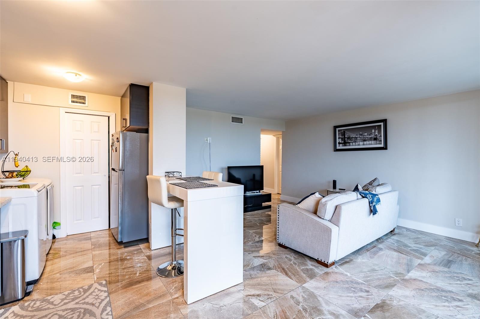 A living room and kitchen area feature tile flooring, a sofa, and a breakfast bar — 3400 Blue Lake Dr # 505, Pompano Beach FL 33064, POMPANO BEACH, FL