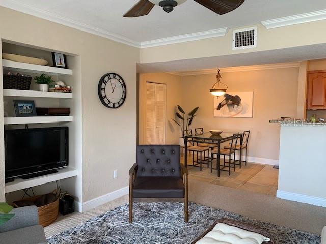 A living room with a built-in media center, an armchair, and an adjacent dining area — 455 ALT 19 S UNIT 65, PALM HARBOR, FL