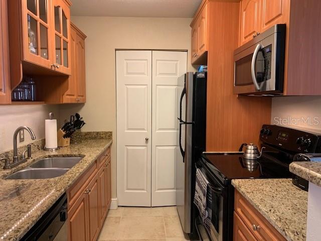 A kitchen features light wood cabinets, granite countertops, a stainless steel microwave, and white doors — 455 ALT 19 S UNIT 65, PALM HARBOR, FL