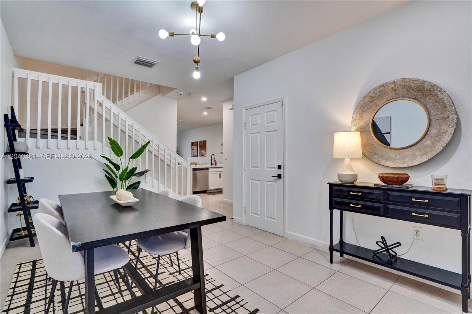 A dining area features a black table, white chairs, a staircase, and a console table — 25341 SW 115th Ct, Homestead FL 33032, HOMESTEAD, FL