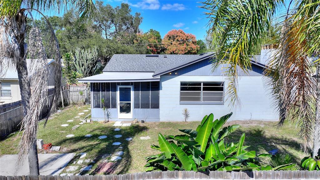 A backyard view of a single-story house with a screened-in porch and palm trees — 221 DOROTHY STREET, AUBURNDALE, FL