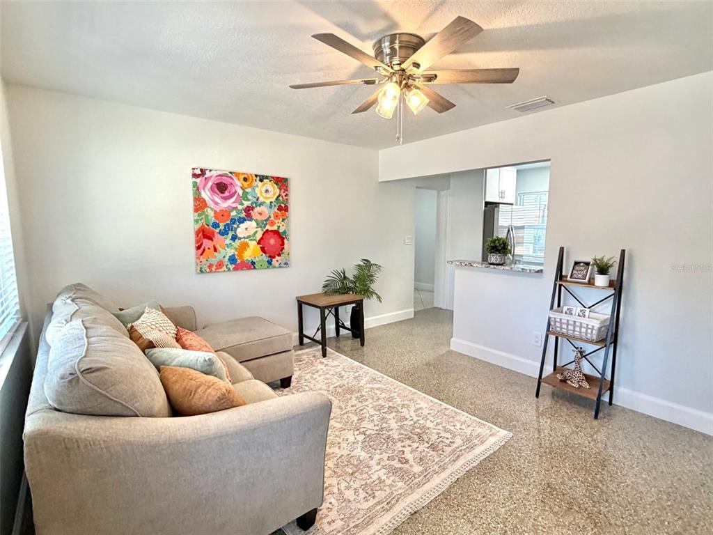 A living room features a gray sectional sofa, a floral wall canvas, and a ceiling fan — 5731 66TH AVENUE N, PINELLAS PARK, FL
