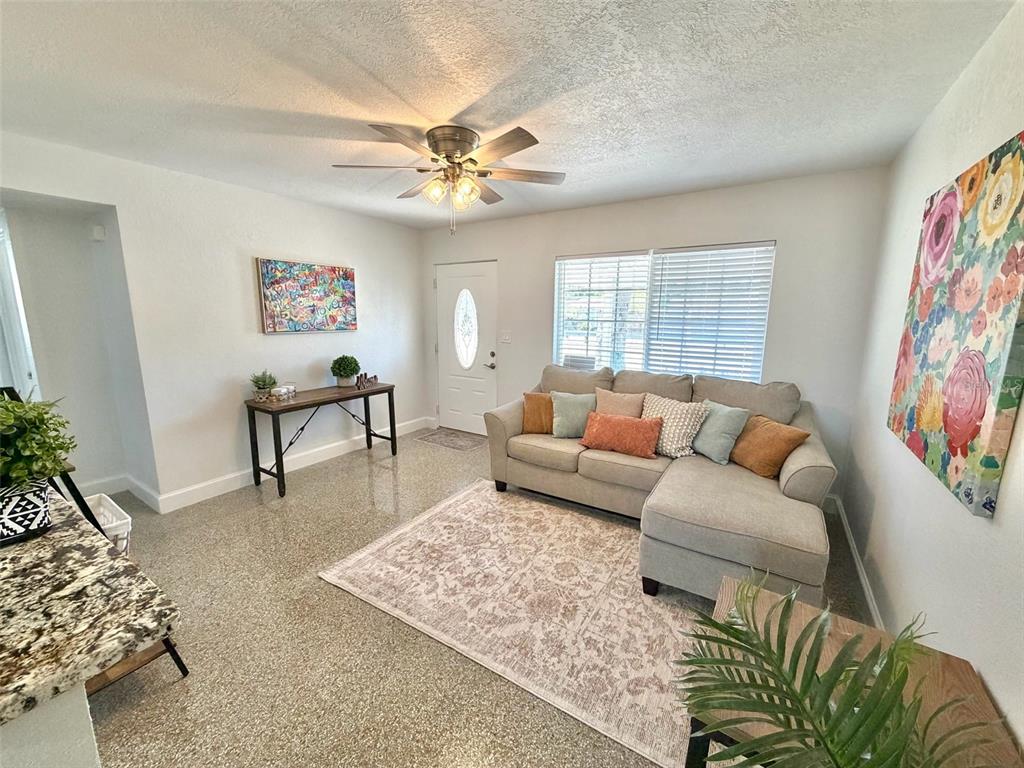 A living room features a sectional sofa, a console table, and terrazzo flooring — 5731 66TH AVENUE N, PINELLAS PARK, FL