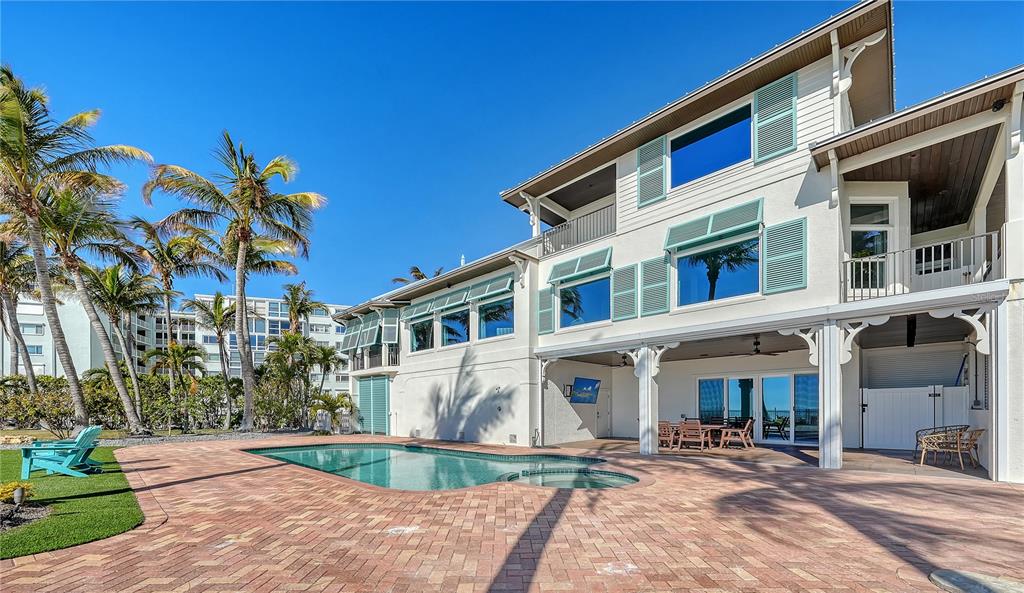 A multi-story house with a pool, patio, and palm trees under a clear blue sky — 95 52ND STREET, HOLMES BEACH, FL