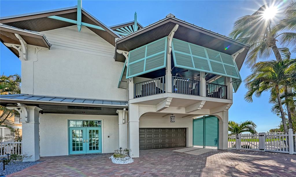 A two-story house with a paved driveway, garage, and a balcony featuring teal shutters — 95 52ND STREET, HOLMES BEACH, FL