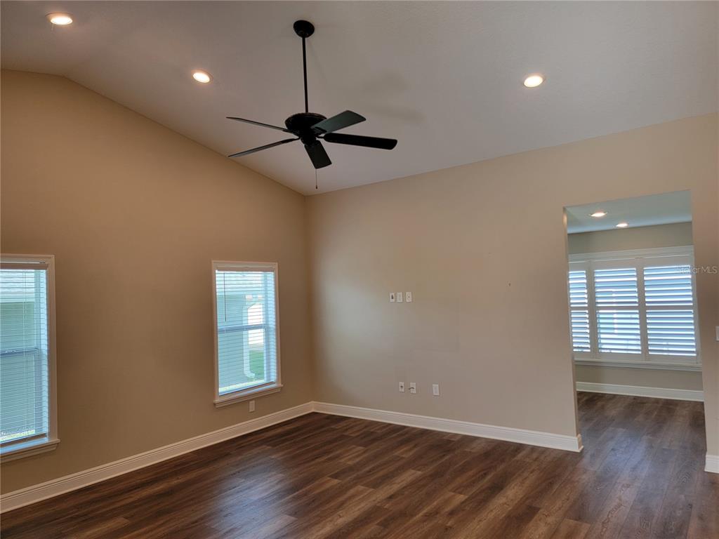 An empty room with wood-look flooring, a vaulted ceiling, a ceiling fan, and two windows — 5986 TEAL TRAIL, LAKELAND, FL