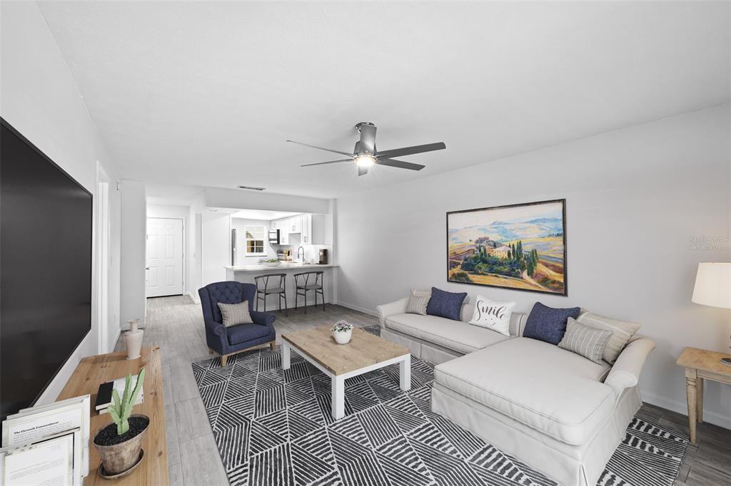 A living room features a white sectional sofa, a patterned rug, and an open kitchen — 3812 N OAK DRIVE UNIT M72, TAMPA, FL