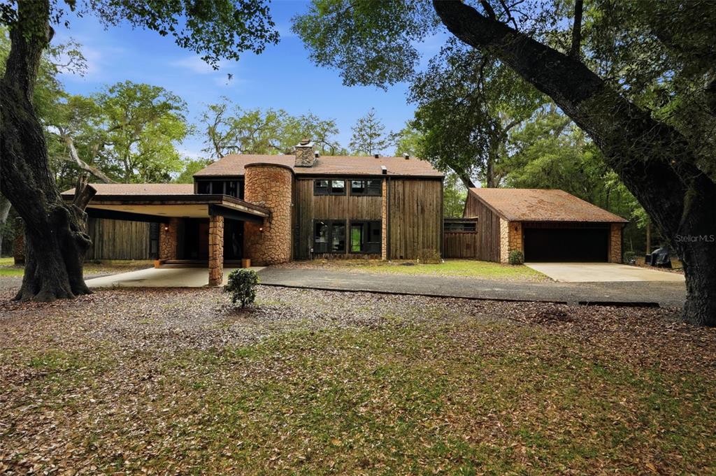 A two-story house with wood siding, a stone chimney, and a detached garage — 16650 NE 53RD LANE, WILLISTON, FL