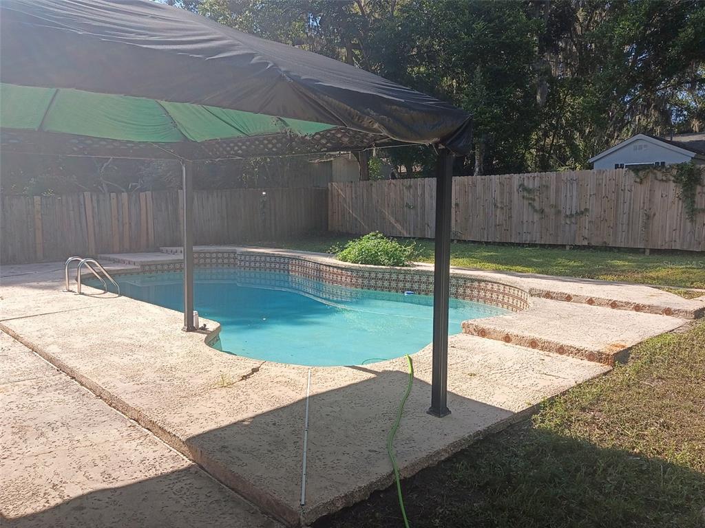 A backyard swimming pool with a gazebo, concrete decking, and a wooden privacy fence — 3740 NE 5TH STREET, OCALA, FL
