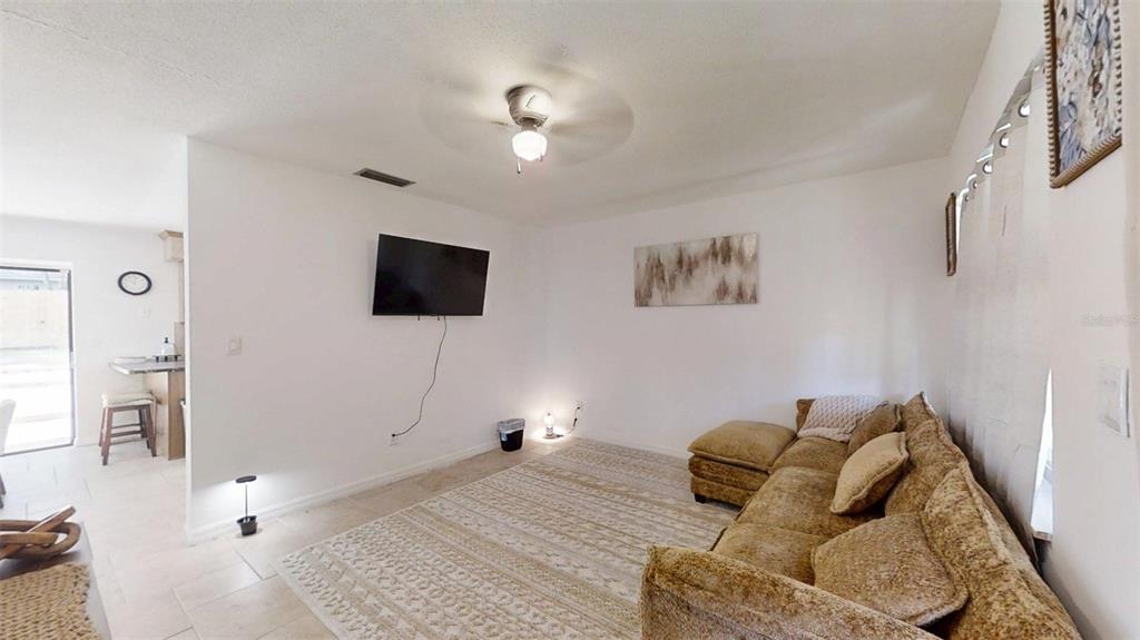 A living room features a tan sectional sofa, a wall-mounted television, and a patterned area rug — 3740 NE 5TH STREET, OCALA, FL