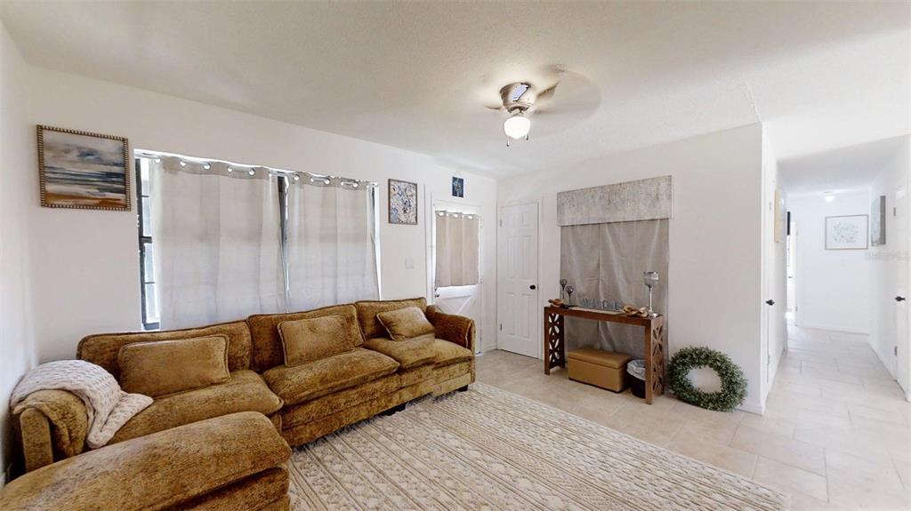 A living room features a brown sectional sofa, a beige area rug, and tile flooring — 3740 NE 5TH STREET, OCALA, FL