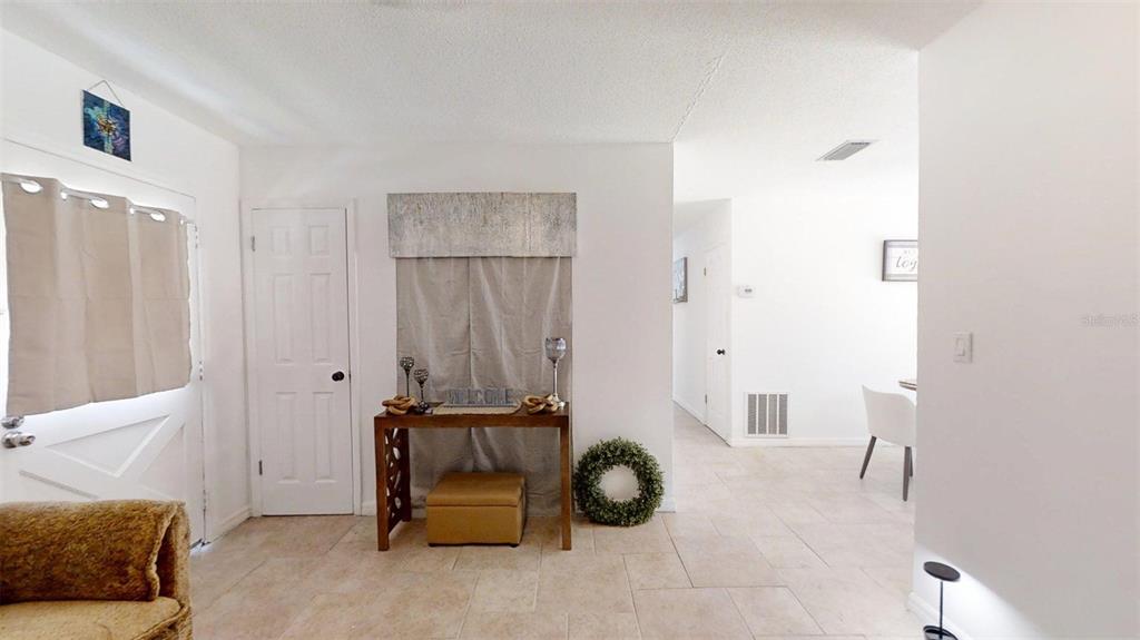 An entryway features a console table, a beige ottoman, and tile flooring — 3740 NE 5TH STREET, OCALA, FL