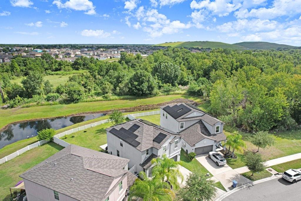An aerial view shows two houses with solar panels on their roofs near a pond — 14855 CRESCENT ROCK DRIVE, WIMAUMA, FL
