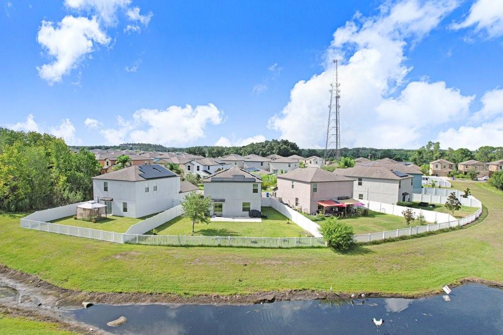 An aerial view shows the backyards of several suburban houses bordering a small pond — 14855 CRESCENT ROCK DRIVE, WIMAUMA, FL