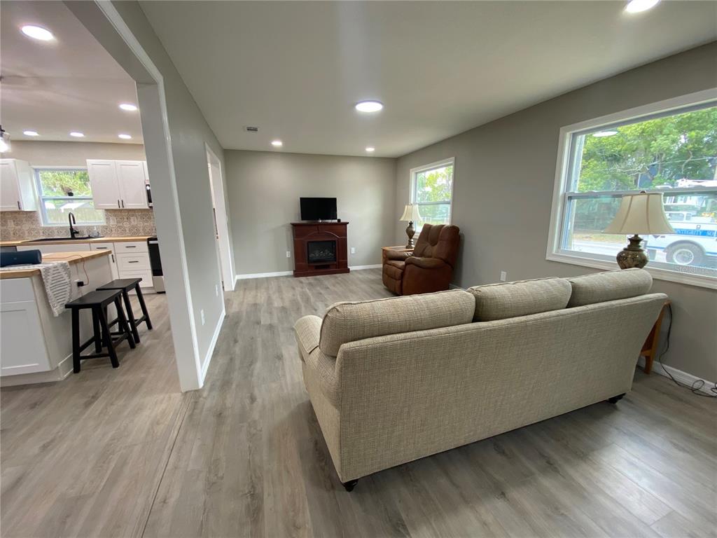 A living room with light wood-look flooring, a fireplace, a sofa, and a recliner — 12704 LACEY DRIVE, NEW PORT RICHEY, FL