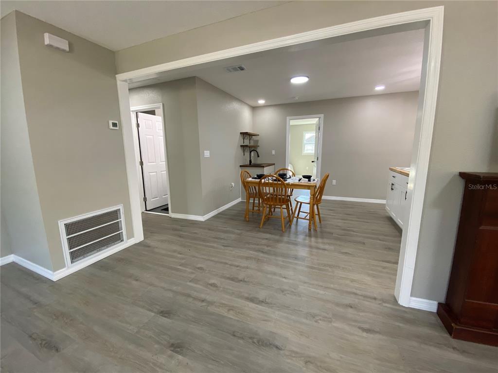 A dining area with wood-toned chairs and a table sits on light gray wood-look flooring — 12704 LACEY DRIVE, NEW PORT RICHEY, FL