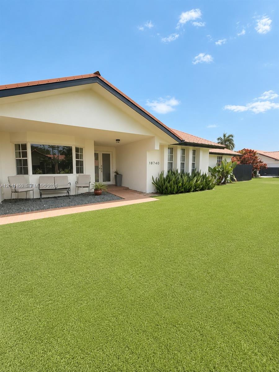 A single-story house with a white exterior, red tile roof, and a large green lawn — 18740 SW 294th Ter, Homestead FL 33030, HOMESTEAD, FL