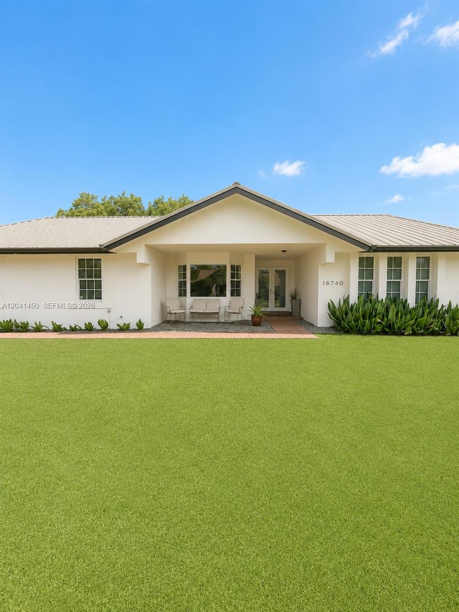 A single-story house with a white exterior, metal roof, and a large front lawn — 18740 SW 294th Ter, Homestead FL 33030, HOMESTEAD, FL