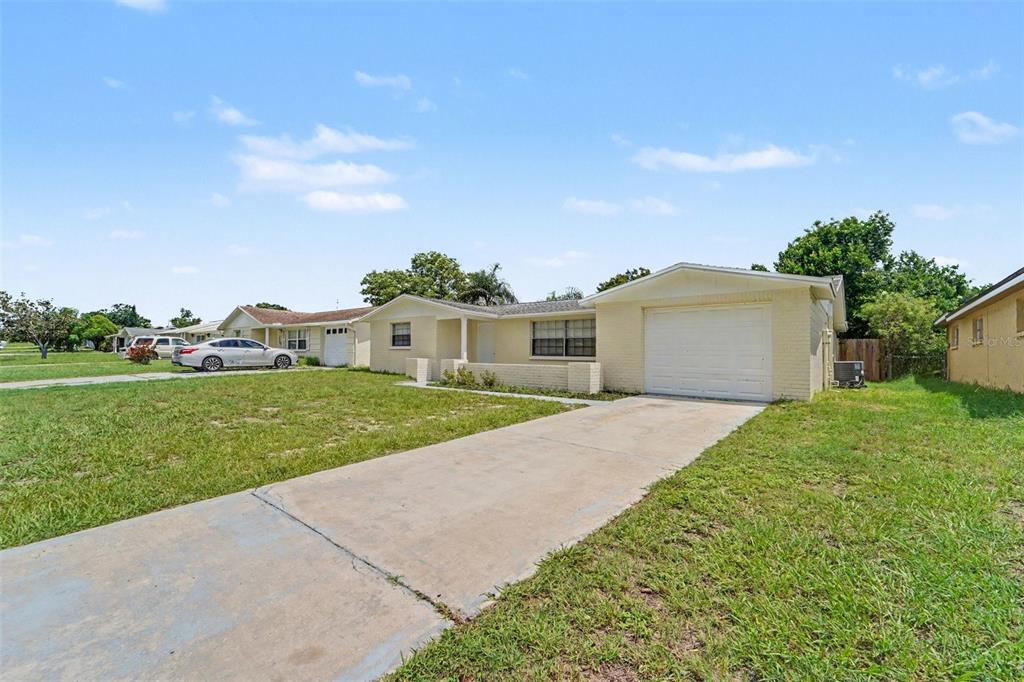 A single-story house with a light-colored brick exterior, a concrete driveway, and a garage — 5102 SCHOOL ROAD, NEW PORT RICHEY, FL