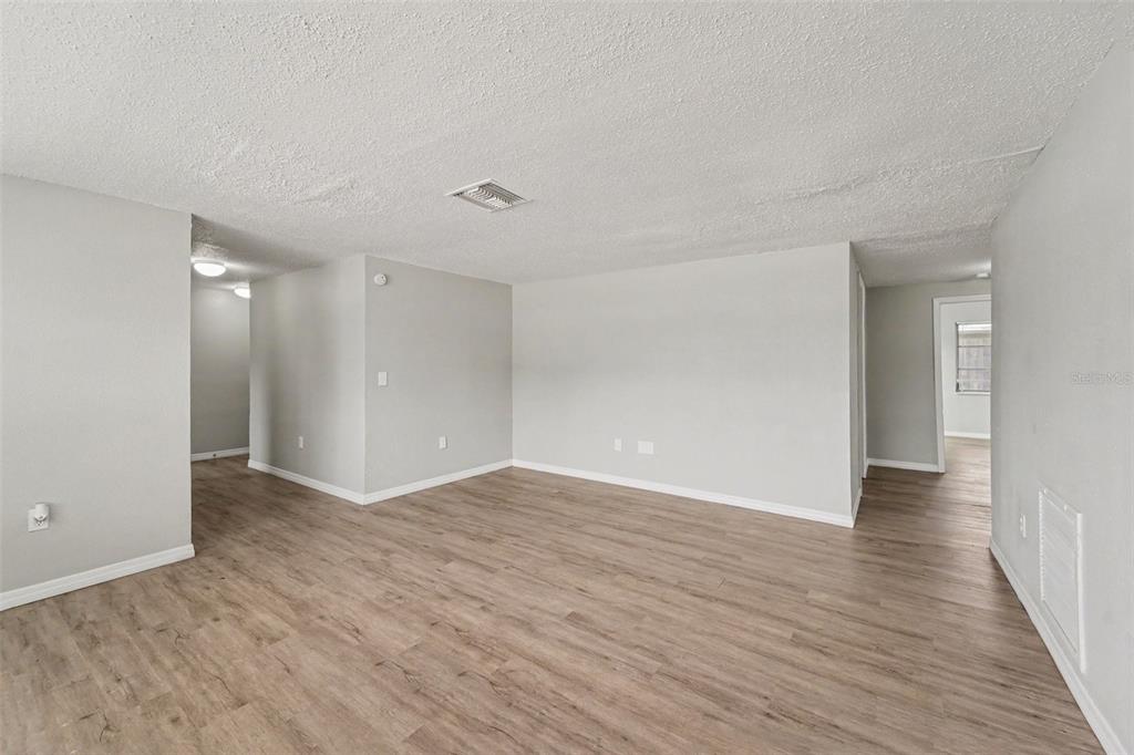 An empty room with light gray walls, wood-look flooring, and a white popcorn ceiling — 5102 SCHOOL ROAD, NEW PORT RICHEY, FL