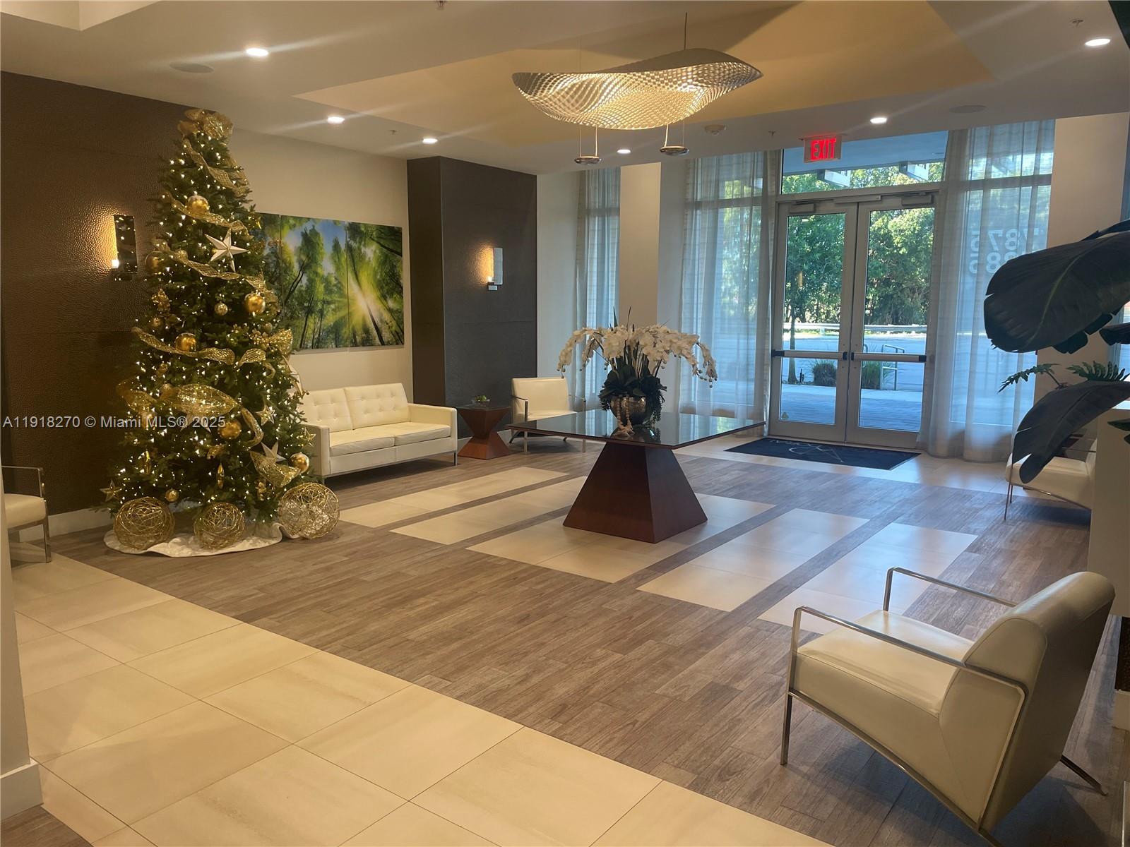 A modern lobby features a decorated Christmas tree, white seating, and a central glass table — 7875 NW 107th Ave # 514, Doral FL 33178, DORAL, FL