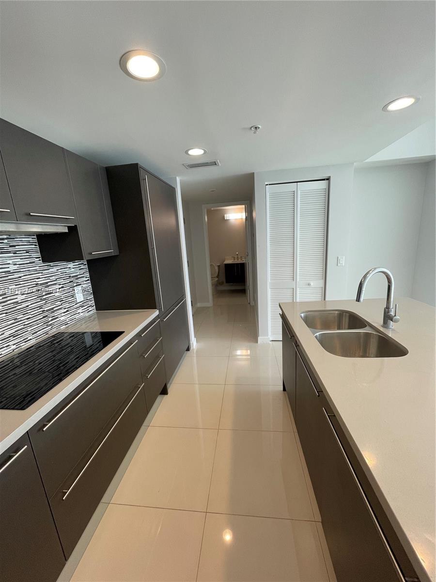 A modern kitchen features dark cabinetry, light countertops, a tiled backsplash, and stainless steel appliances — 7875 NW 107th Ave # 514, Doral FL 33178, DORAL, FL