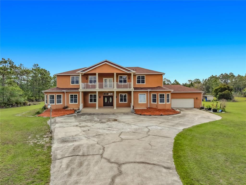 A large, two-story orange house with a balcony and a cracked concrete driveway — 6031 BANCROFT BOULEVARD, ORLANDO, FL