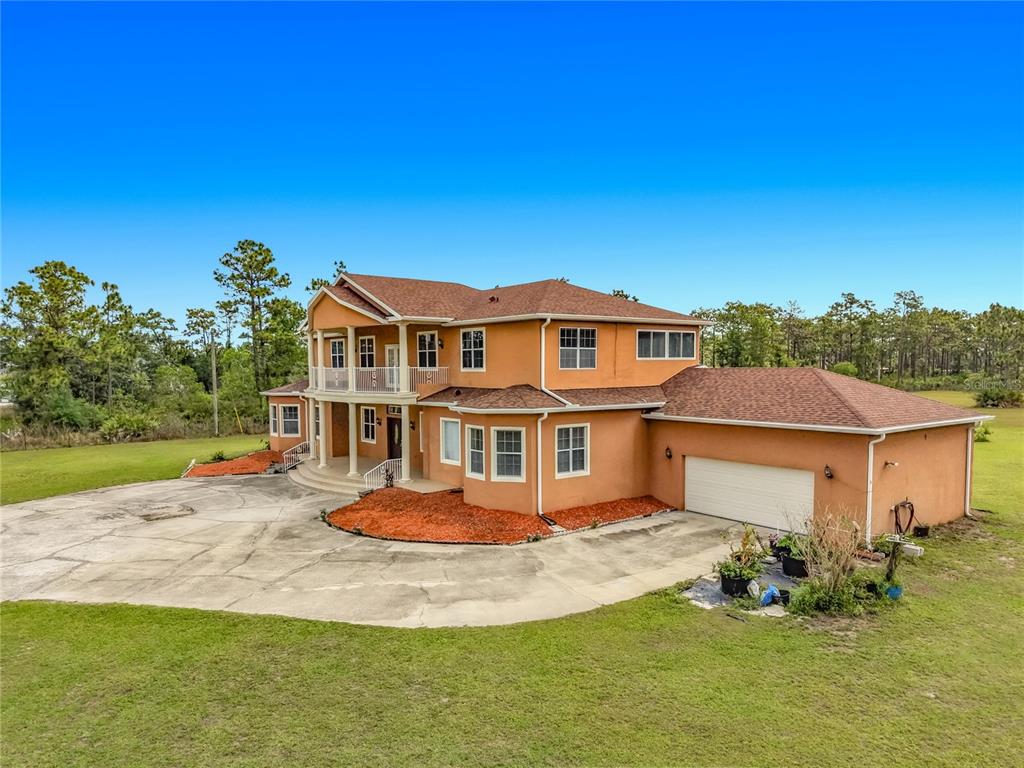 A two-story orange stucco house with a large concrete driveway and a two-car garage — 6031 BANCROFT BOULEVARD, ORLANDO, FL