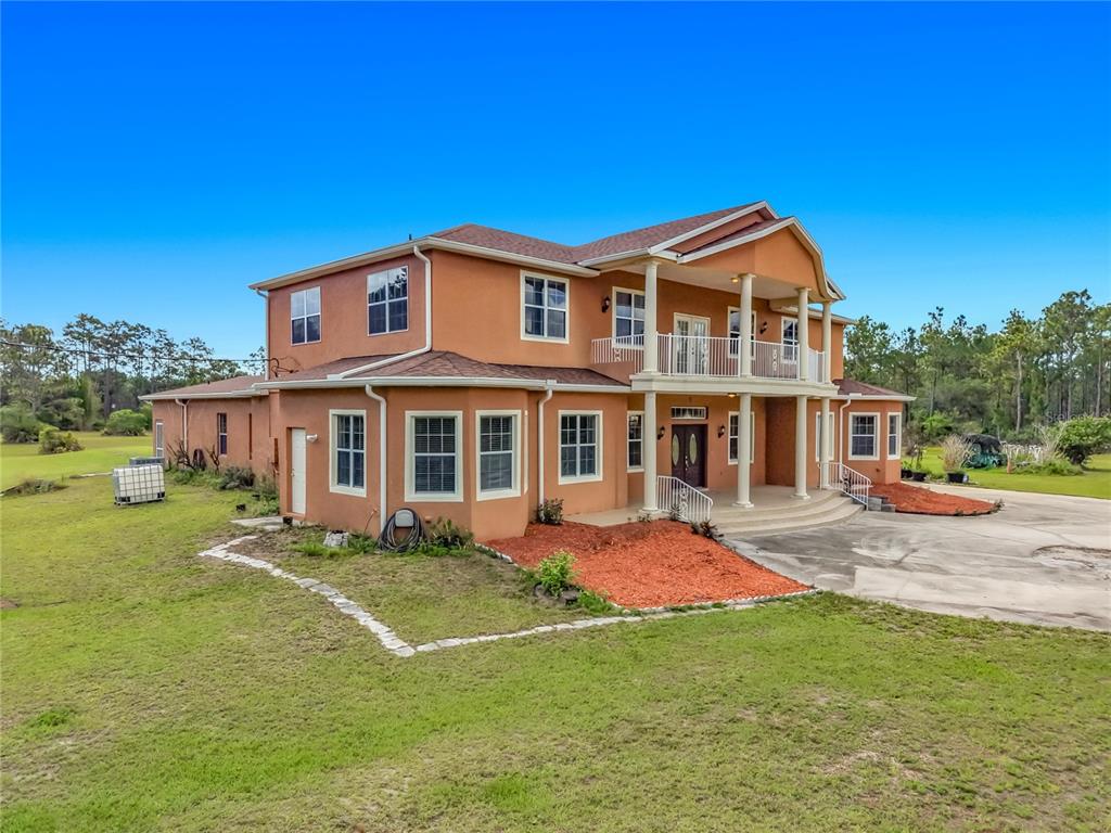 A two-story, orange-stucco house with a front porch, balcony, and a large concrete driveway — 6031 BANCROFT BOULEVARD, ORLANDO, FL