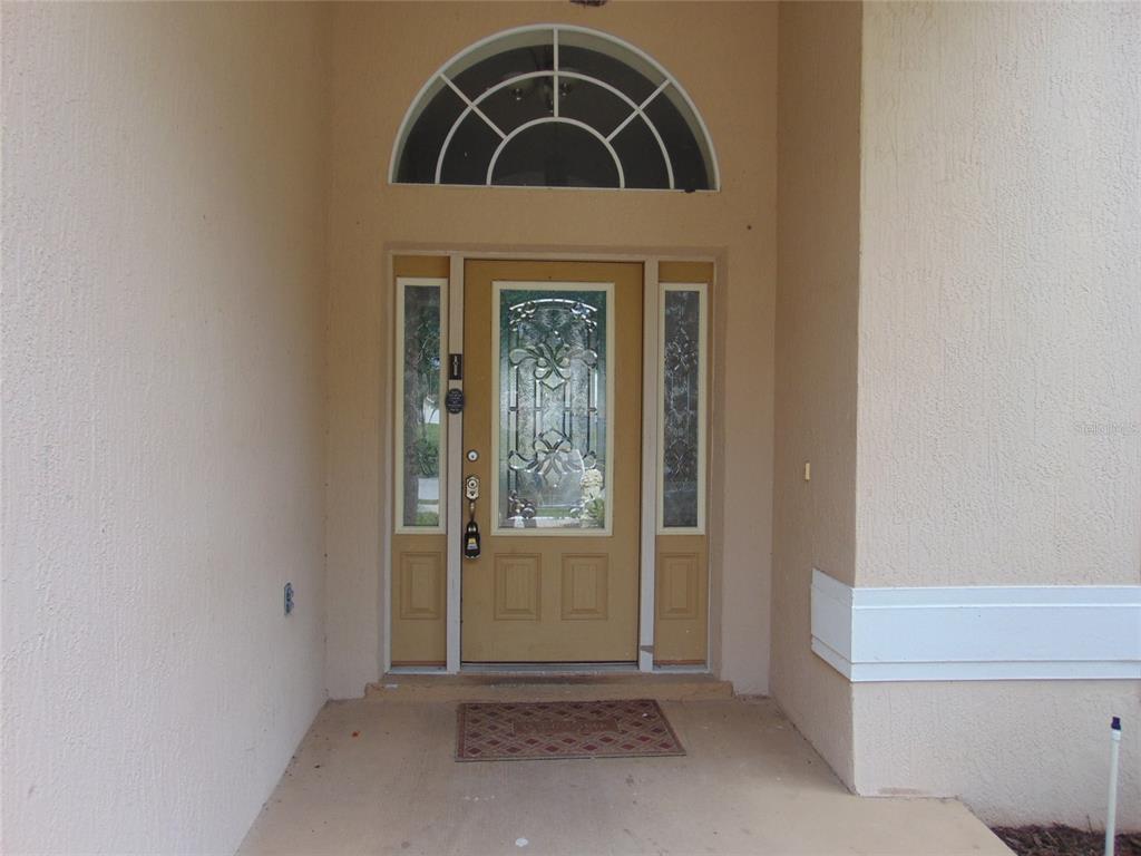 A tan front door with a decorative glass insert and sidelights under an arched transom window — 3126 SAMOSA HILL CIRCLE, CLERMONT, FL
