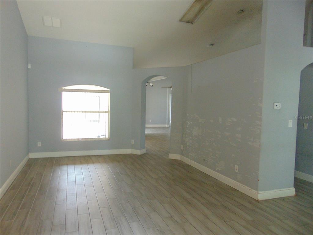 An empty room with light blue walls, wood-look tile flooring, and an arched doorway — 3126 SAMOSA HILL CIRCLE, CLERMONT, FL