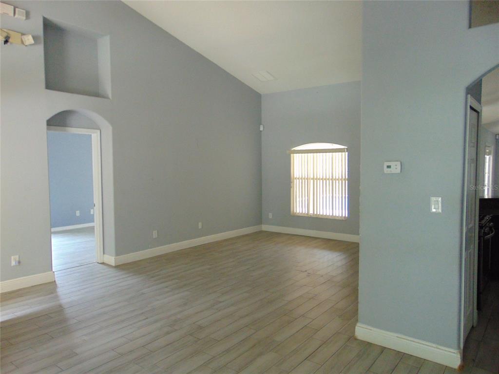 An empty room with light blue walls, vaulted ceilings, and wood-look tile flooring — 3126 SAMOSA HILL CIRCLE, CLERMONT, FL
