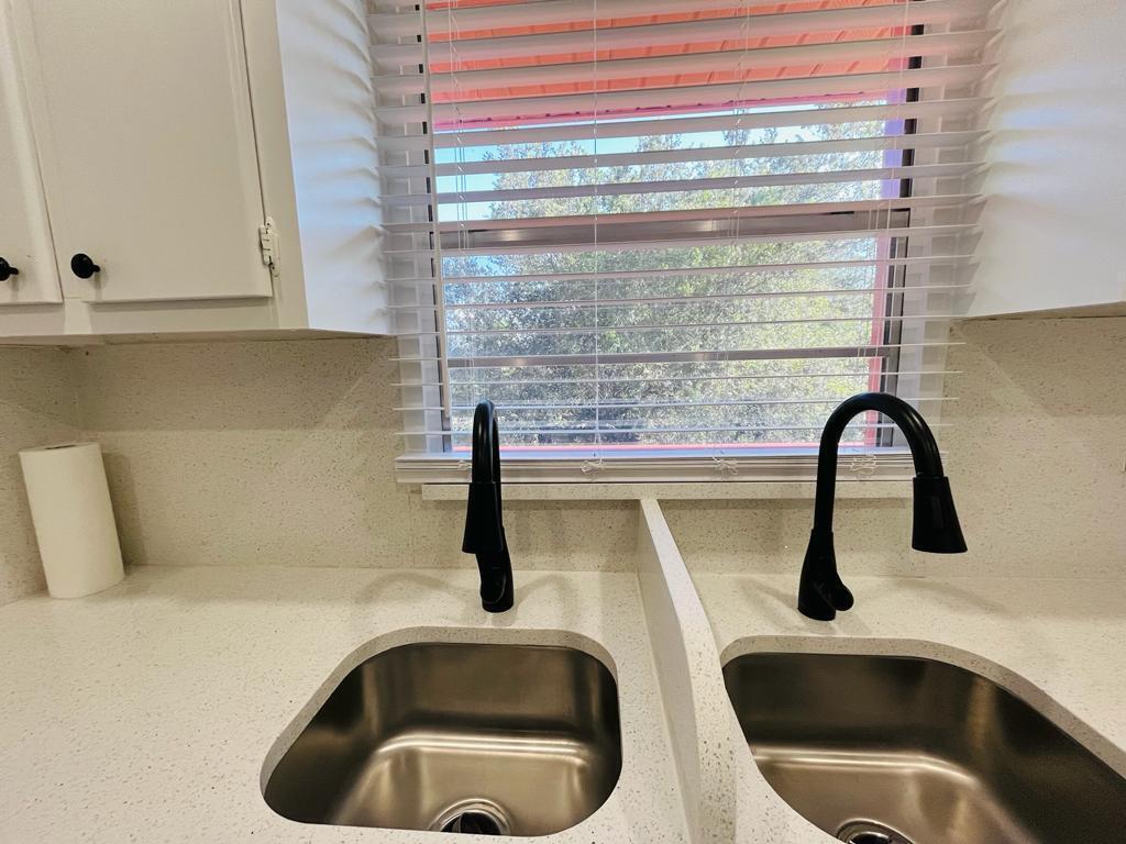 A kitchen sink area features two black faucets, stainless steel basins, and white speckled countertops — 11 Golfs Edge E, West Palm Beach FL 33417, WEST PALM BEACH, FL