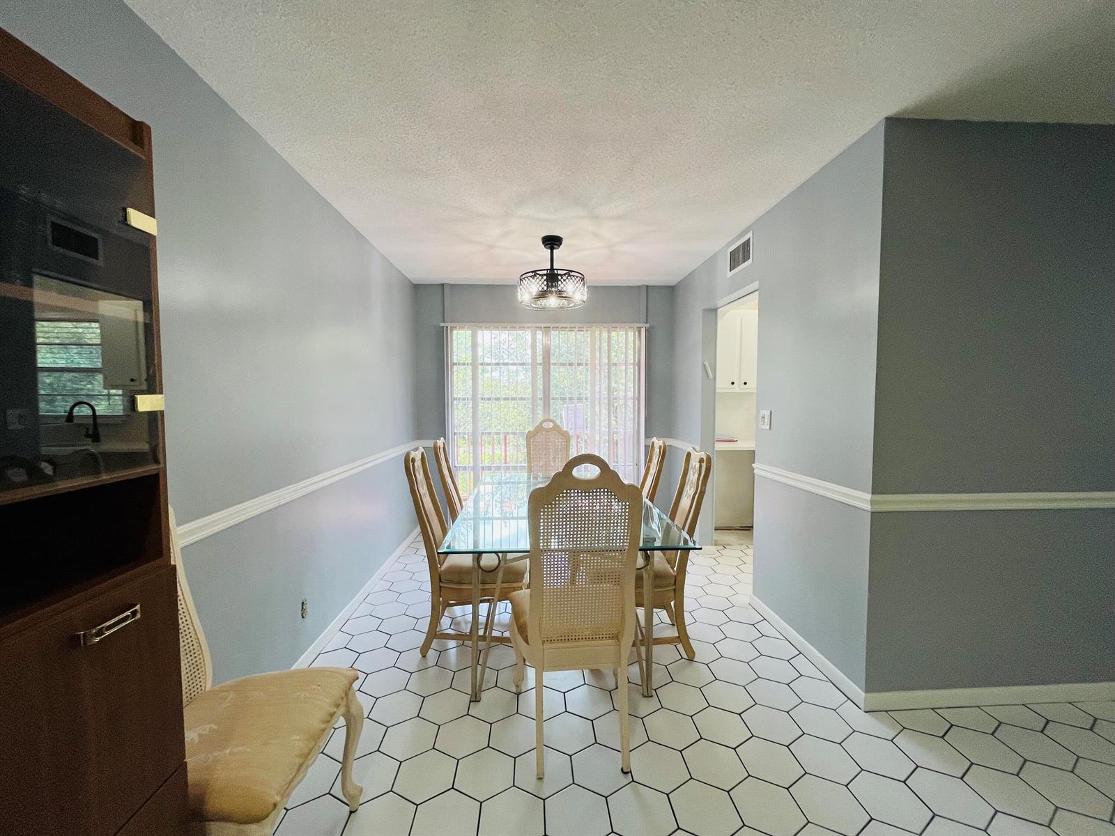 A dining room features a glass-top table, cane-back chairs, and white hexagonal floor tiles — 11 Golfs Edge E, West Palm Beach FL 33417, WEST PALM BEACH, FL