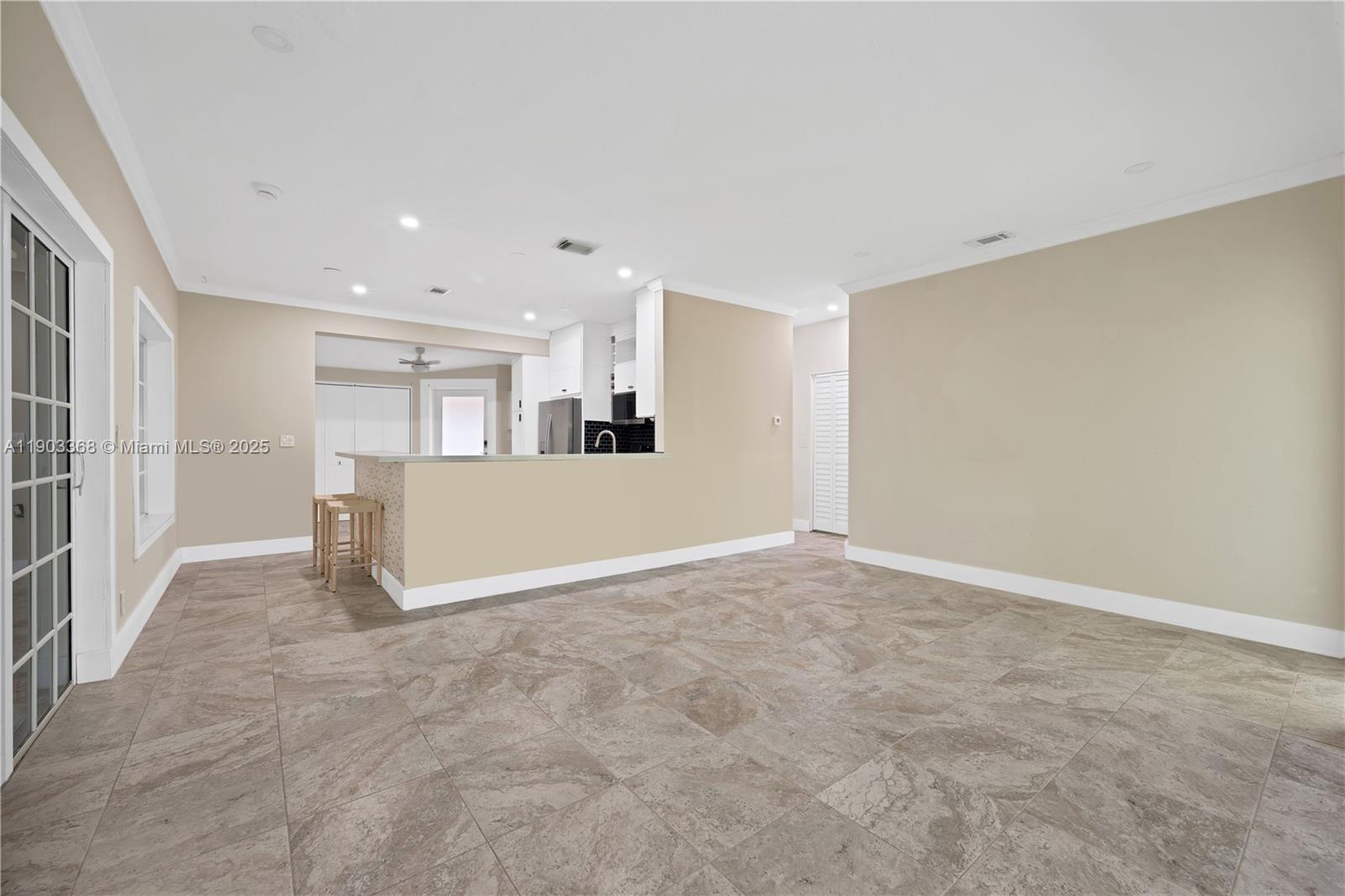 An open-concept living area features beige walls, tile flooring, and a kitchen breakfast bar — 818 NE 3rd St, Hallandale Beach FL 33009, HALLANDALE BEACH, FL