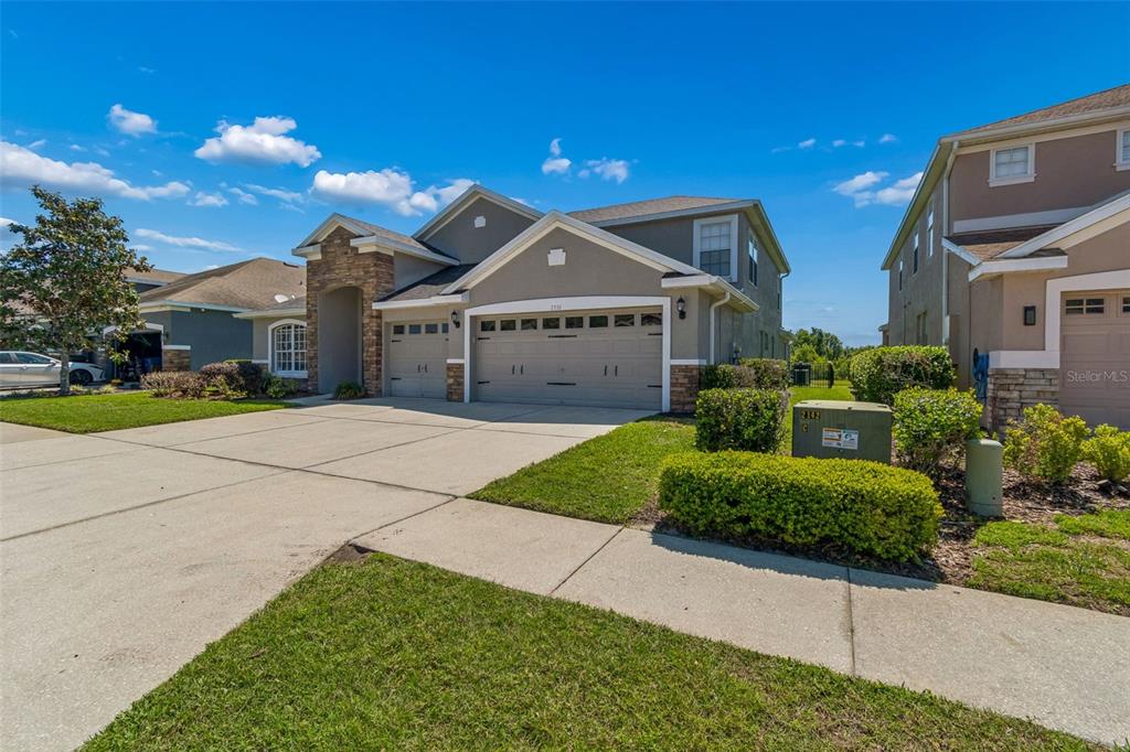 A two-story suburban house with a three-car garage and stone accents on the exterior — 2336 NESSLEWOOD DRIVE, WESLEY CHAPEL, FL