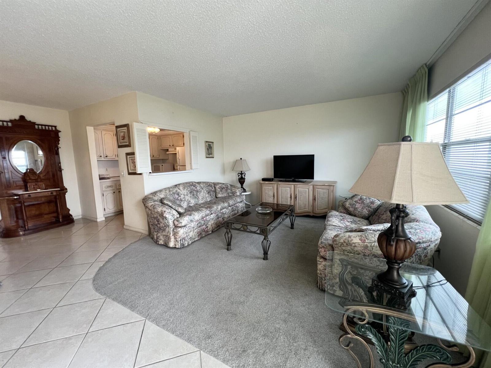 A living room features floral sofas, a glass coffee table, and a large wooden hutch — 4116 Cambridge E, Deerfield Beach FL 33442, DEERFIELD BEACH, FL