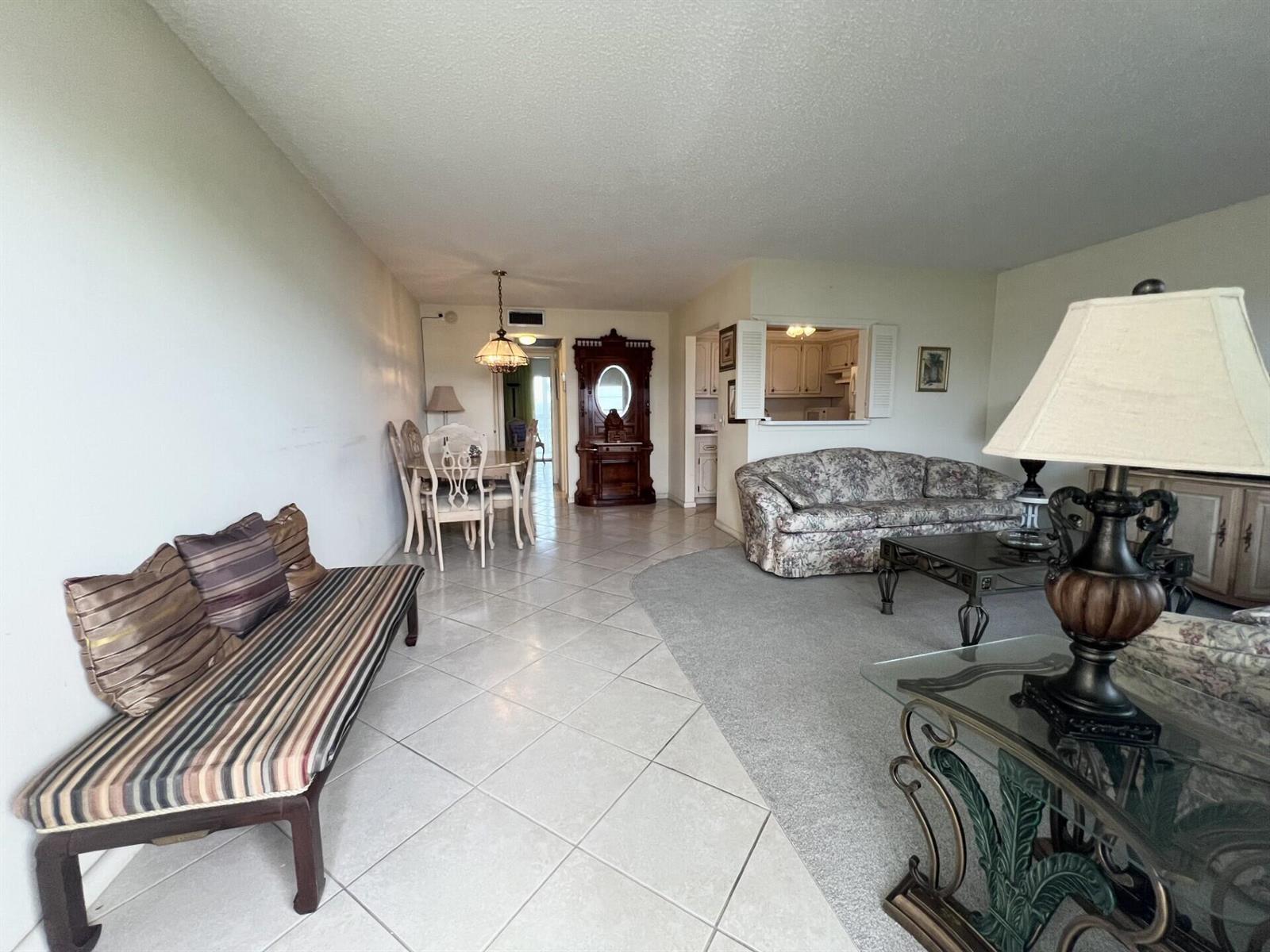 A living and dining area features tile floors, a carpeted seating section, and a pass-through kitchen — 4116 Cambridge E, Deerfield Beach FL 33442, DEERFIELD BEACH, FL