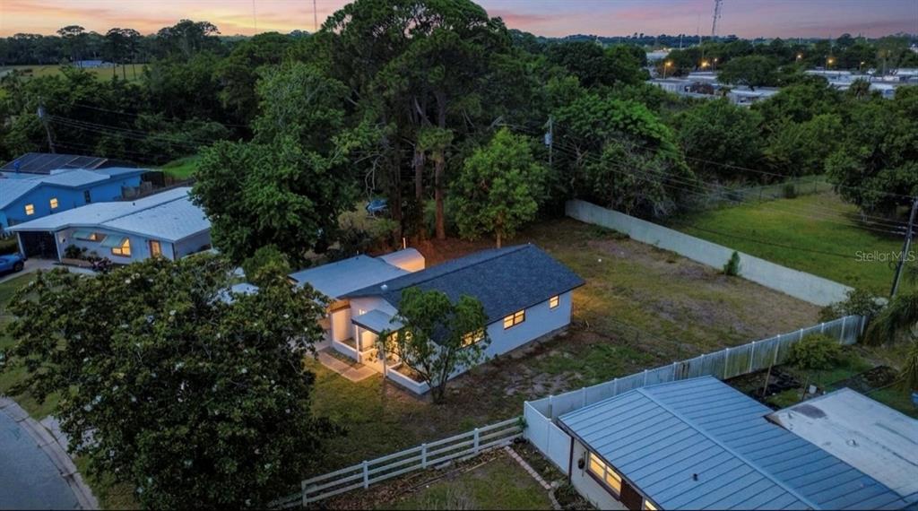 An aerial view shows a single-story house with a dark roof and a large yard — 1011 MONTCLAIR ROAD, COCOA, FL
