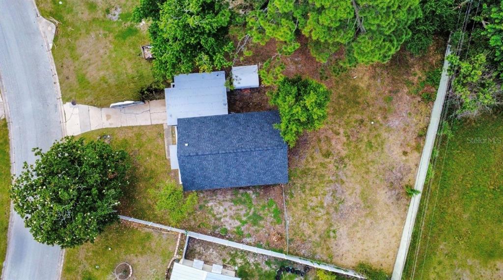 An aerial view shows a house with a dark roof surrounded by trees and grass — 1011 MONTCLAIR ROAD, COCOA, FL
